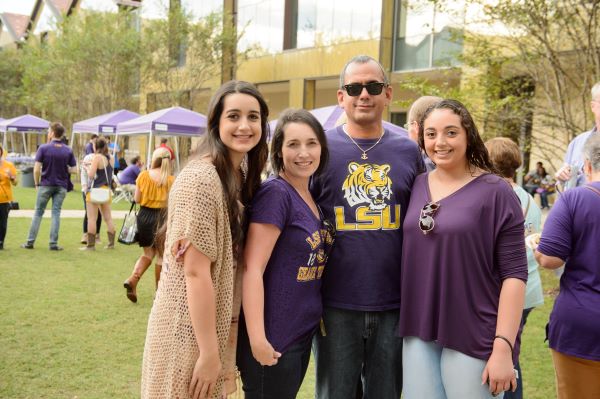 A group of people in LSU gear smile in the BEC courtyard.