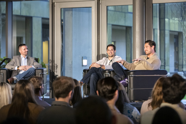 Three men on a stage sitting in chairs.