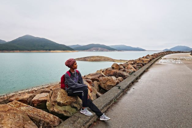 Woman sits on wall near a river.