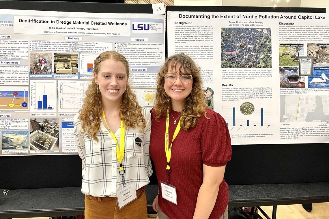 Two students smiling for photo in front of their research posters